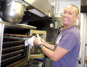 Jerome Chang ’99 places a batch of his acclaimed chocolate bread pudding into the oven at the DessertTruck Works kitchen. PHOTO: NATHALIE ALONSO ’08
